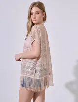 Kaftan blanco calado con cuello a la base, escote en V y lazo de ajuste. Terminación de ruedo con flecos.