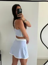 Conjunto deportivo lila compuesto por un top corto con tirantes finos y una minifalda con short incorporado.