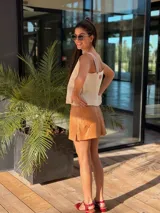 Musculosa marrón de gamuza con bordados blancos en el frente y detalle de flecos en los hombros. Tiene cuello redondo y sisas amplias con terminación de crochet.