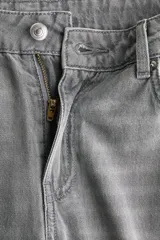 Jean de corte wide leg y tiro medio en denim color gris deslavado, con diseño de cinco bolsillos y cierre frontal con botón y cremallera.