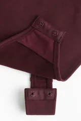 Body tanga modelador color borravino con efecto vientre plano y copas sin aros que realzan el busto. Cuenta con breteles finos ajustables y diseño sin costuras laterales.