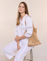 Cartera tipo shopper con estructura externa de tejido tipo red en color tostado, base sólida reforzada y correas dobles integradas de cuero sintético. Cuenta con compartimento principal interior con cierre.