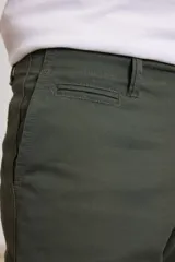 Pantalón chino de hombre color verde oscuro, corte slim, confeccionado en algodón con elastano, con triple pespunte en las costuras y botones al tono.