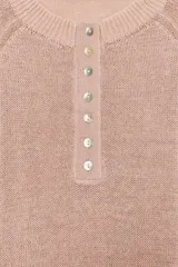 Sweater de punto color beige con cuello redondo, manga larga y cierre frontal parcial con botones. Presenta terminaciones en rib en cuello, puños y dobladillo.