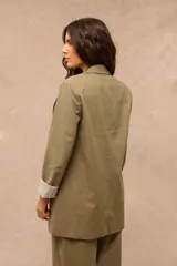 Blazer verde oliva de corte largo y holgado, con solapas clásicas, bolsillos frontales con solapa y mangas largas con vuelta estampada a rayas.