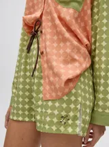 Short de corte boxy confeccionado en viscosa con estampado geométrico de estrellas en tonos rosados. Presenta una pretina elástica en color naranja y cordón de ajuste en color marrón.