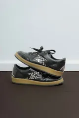 Championes negros de cuero con apliques metálicos plateados y suela color caramelo.