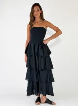 Vestido largo color crudo, sin tirantes, con cuerpo fruncido elástico tipo nido de abeja y falda de capas con volados con bordes deshilachados.