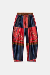 Pantalón de tiro alto con cintura elástica y bolsillos delanteros. Presenta un estampado de cadenas, cinturones y rayas en bloques de color rojo y azul marino. Incluye un cinturón del mismo tejido.
