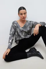 Blusa beige con estampado de arabescos en azul, con escote en V y mangas largas.