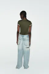 Camiseta de corte slim fit, color verde militar, con cuello redondo y manga corta. Presenta vivos de contraste blancos en el ruedo de las mangas y en el bajo.