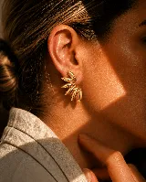 Aros tipo ear cuff de diseño abanico, compuestos por múltiples piezas metálicas en forma de pétalo o gota dispuestas en semicírculo.