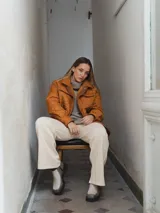 Campera acolchada color ladrillo con cuello marrón de pana, cierre frontal con botones a presión y bolsillos laterales.