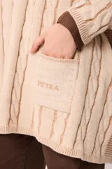 Sweater de punto con diseño de trenzas verticales, color crudo y camel, con bolsillos frontales y detalle de logo bordado. Presenta un corte holgado y mangas largas.