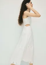 Vestido largo de algodón blanco con diseño sin mangas, cuello redondo y aberturas laterales en la cintura. Presenta un delicado bordado floral calado en la parte superior y en el ruedo, con una falda de corte evasé.