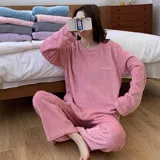 Conjunto de pijama de dos piezas confeccionado en tela de plush texturizada con diseño de rayas verticales en relieve. Incluye una remera de manga larga con cuello redondo y un pantalón de corte holgado. La remera presenta un pequeño bordado decorativo en el pecho.