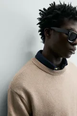 Sweater de punto color beige, de corte regular fit, con cuello redondo y manga larga. Presenta terminaciones en rib en cuello, puños y dobladillo.