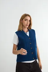 Chaleco tejido de punto color bordó, con escote en V, cierre frontal con botones y diseño de trenzas verticales. Cuenta con dos bolsillos frontales y terminaciones acanaladas.