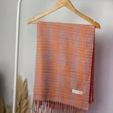 Pashmina rectangular con diseño a cuadros en tonos rosa y gris, con flecos en los bordes.