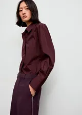 Pantalon de corte recto en color morado oscuro, con tiro medio y detalle de ribete (piping) en contraste a lo largo de las piernas. Cuenta con bolsillos laterales, cierre oculto y trabillas para cinturón.