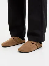 Zueco de gamuza color cognac, con puntera redonda, tira ajustable con hebilla, suela de corcho y base de goma.