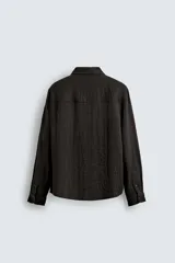 Camisa de corte relajado confeccionada en tejido fluido con mezcla de viscosa. Presenta cuello solapa, cierre frontal con botones y manga larga con puños abotonados.