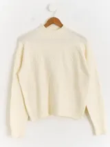 Sweater de punto color blanco con cuello polera, manga larga y diseño bordado al tono con motivos florales en el frente y las mangas.
