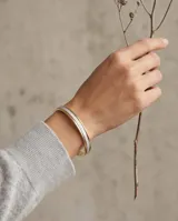 Pulsera esclava rígida de plata 925 y lámina de oro 18k, con diseño bicolor y pavé de circonias en la franja central.