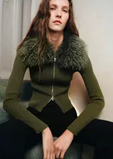 Cardigan de punto acanalado en color verde oliva, con diseño entallado, cierre frontal de cremallera y cuello de pelo sintético al tono.