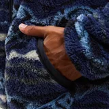 Canguro de sherpa con cierre frontal completo, capucha y bolsillos laterales. Presenta un estampado geométrico multicolor en tonos azules, grises y blancos. Confeccionado en tejido térmico de textura gruesa.