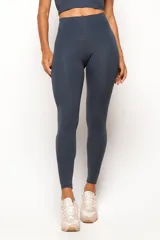 Conjunto deportivo de dos piezas en color gris oscuro, compuesto por un top de tirantes anchos con escote redondo y largo extendido con recortes en la cintura, y una calza de tiro alto con costuras modeladoras.