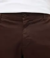 Pantalón slim de sarga lavada color marrón, con cierre de botón y cremallera, trabillas para cinturón y bolsillos laterales y traseros.