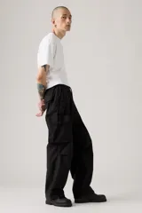 Pantalón cargo negro de corte holgado, con cintura elástica y cordón ajustable. Presenta bolsillos laterales y bolsillos cargo con solapa en los muslos.