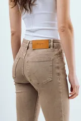 Jean de corte recto y tiro medio color tostado, confeccionado en denim con silueta relajada, bolsillos clásicos y cierre frontal con botón y cremallera.