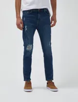 Pantalón de jean azul oscuro con roturas grandes en las rodillas y pequeñas roturas en los muslos.