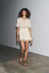 Blusa de algodón color crudo con detalle de bordados y crochet. Cuello redondo, manga corta y cierre frontal con botones.