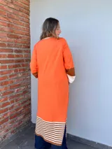 Saco largo color naranja de tejido de punto en algodón, con solapas y bolsillos de cuero marrón.