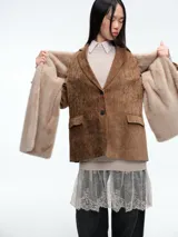 Blazer de pana color marrón con solapas clásicas, cierre frontal de dos botones y bolsillos laterales con solapa.