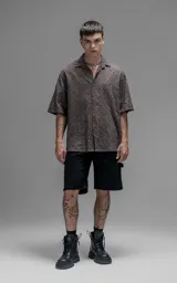 Camisa de manga corta con calce oversize y cuello abierto, confeccionada en algodón con diseño de bordado tipo broderie y efecto de desgaste en el color.