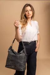 Cartera tipo bandolera de gran tamaño, confeccionada en cuero sintético con acabado desgastado. Cuenta con una asa corta fija, una correa larga regulable y extraíble, y una placa metálica con la marca en la parte frontal.