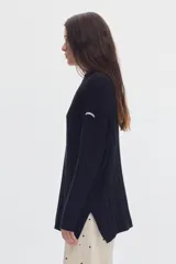 Buzo negro de tejido de ochos, con cuello redondo y diseño oversized de corte largo y amplio con tajos laterales.