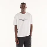 Remera New Balance Trackside de algodón, color blanco, de corte cuadrado y relajado, con cuello redondo y mangas cortas. Presenta estampado frontal en relieve con el logotipo de la marca.