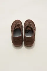 Zapatillas de estilo urbano color chocolate, confeccionadas en material textil tipo gamuza, con cordones al tono y suela de goma plana.