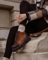 Botinetas de cuero con diseño bicolor en tonos negro y marrón, con suela track gruesa y cierre frontal.