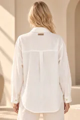 Camisa de lino color mostaza, de corte clásico con cuello camisero, manga larga y cierre frontal abotonado.
