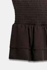 Shorts cortos de color marrón con cintura elástica de nido de abeja y volantes en el dobladillo.