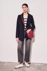 Blazer negro de corte clásico con solapas y mangas largas con puños con rayas verticales.