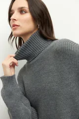 Polera gris de tejido de punto, corte oversized, cuello alto y mangas largas.