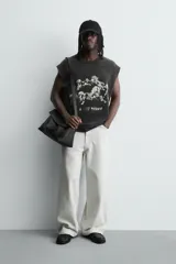 Camiseta sin mangas (tank top) de algodón con efecto lavado oscuro, corte cropped y cuello redondo. Presenta un estampado frontal en blanco con varios caballos en estilo gótico y texto en la parte inferior.