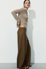 Pantalón de tiro medio confeccionado en mezcla de lino, con diseño de pierna recta y detalle de superposición frontal tipo pareo. Cuenta con cierre frontal mediante cremallera, botón y gancho metálico.
